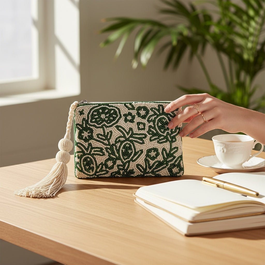 JOYCO emerald green and white beaded embroidered pouch with a decorative tassel on a wooden desk