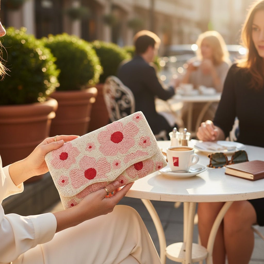 JOYCO Fileur clutch with pink floral embroidery held by a woman at an outdoor cafe table