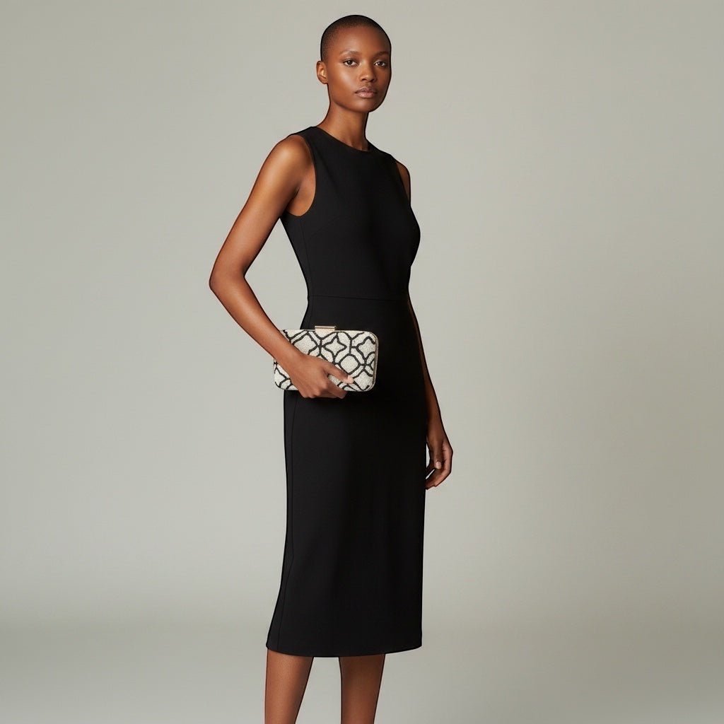 Model holding a JOYCO Maison Blanc black and white embroidered box clutch with a sleek black midi dress
