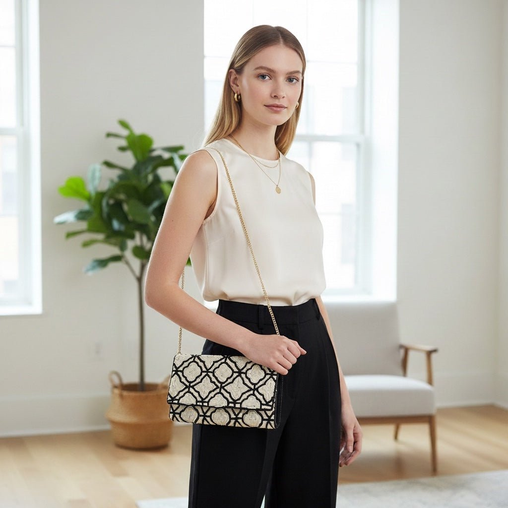 JOYCO Maison Blanc embroidered clutch with geometric black and white pattern worn by a woman with a gold chain strap.