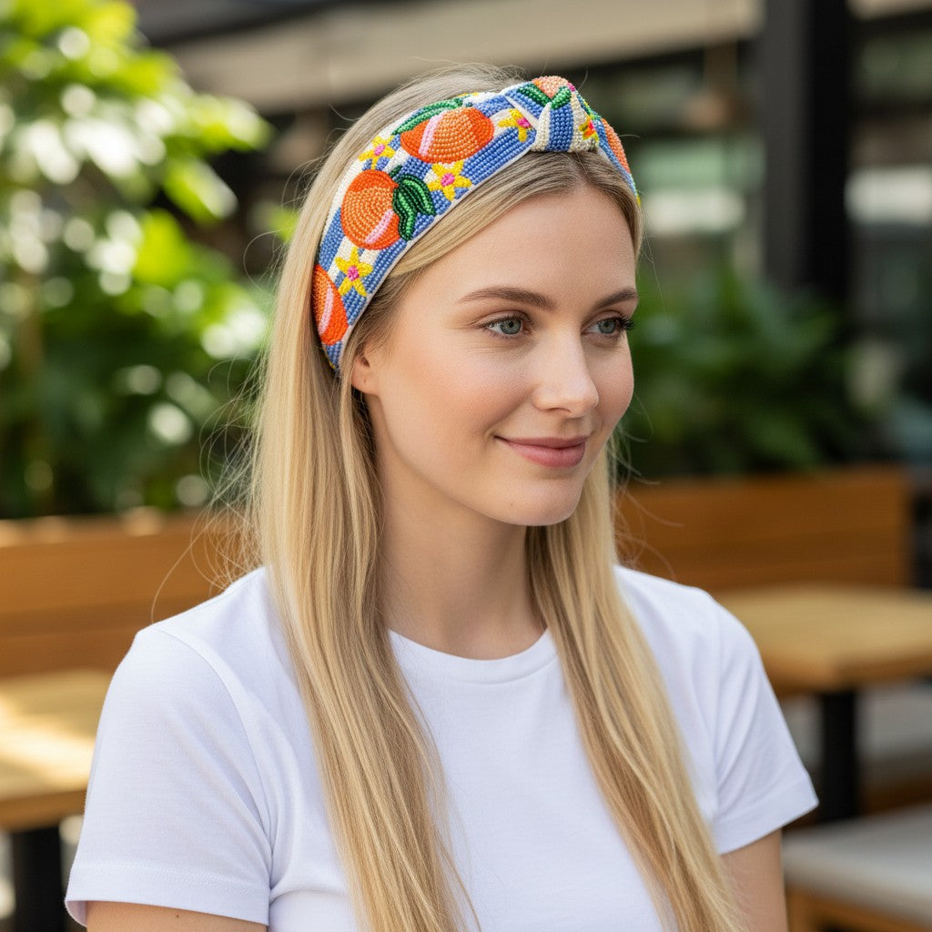 JOYCO Peach Riviera headband with intricate orange and floral bead embroidery worn by a blonde woman