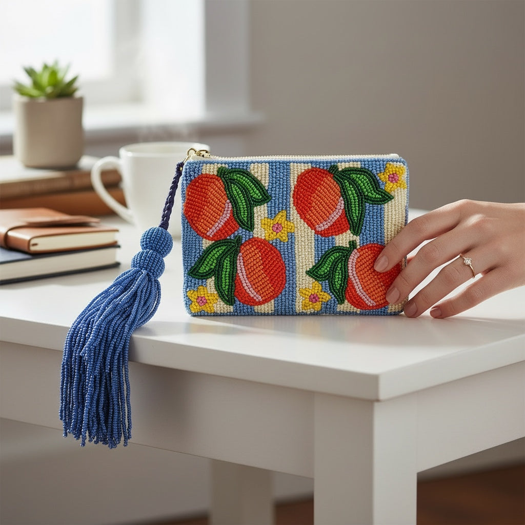 JOYCO Peach Riviera embroidered pouch with blue and white stripes, peach motifs, and a large blue beaded tassel.