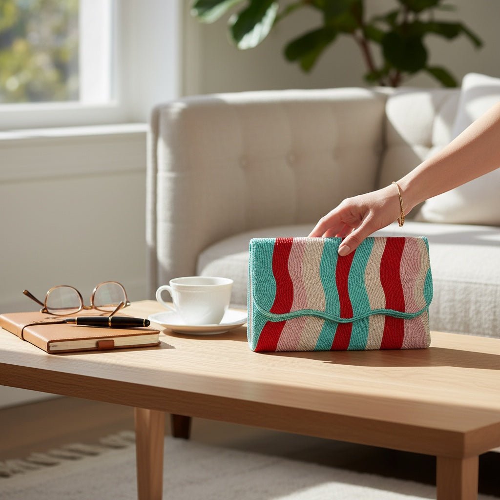 JOYCO rainbow embroidered clutch with wavy beaded patterns held on a wooden coffee table in a bright living room.