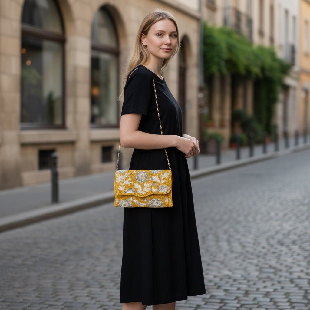 JOYCO Soleil Bloom yellow embroidered clutch with floral stitching worn by a woman in a black dress on a city street.